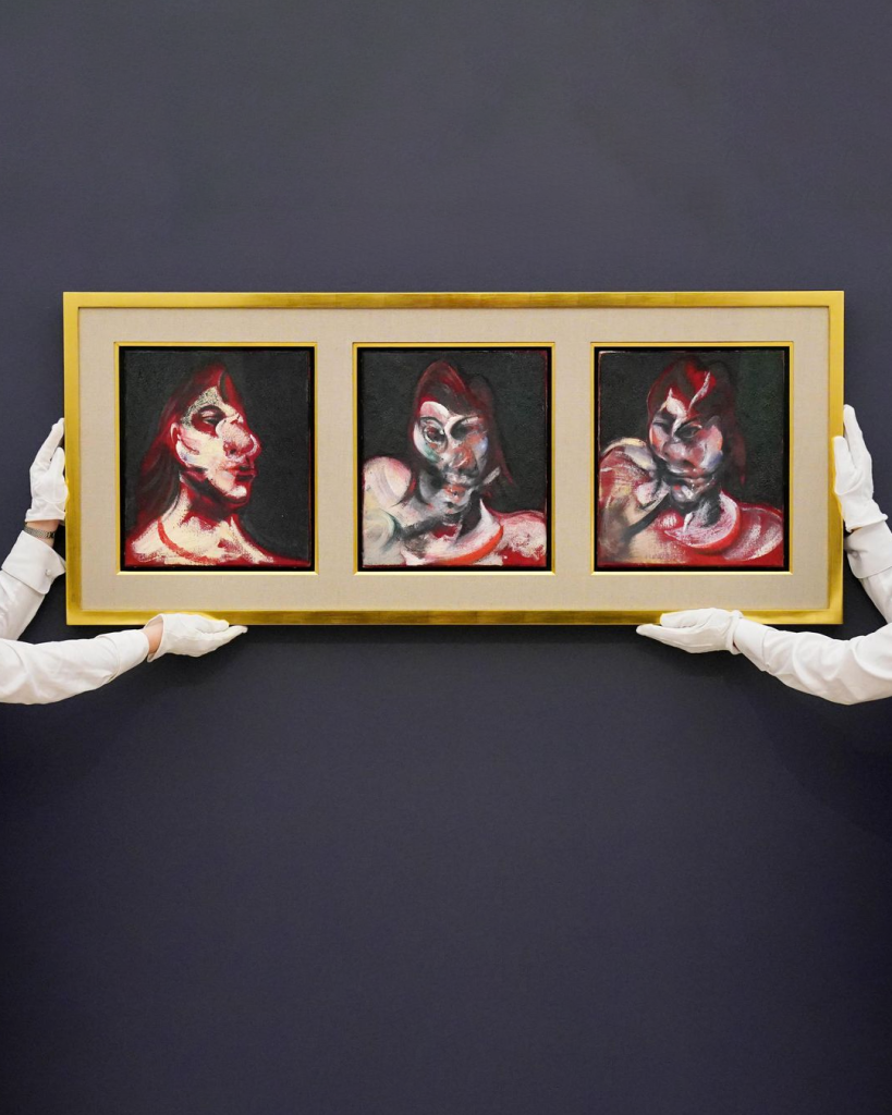 Obra de Francis Bacon sendo segurada por duas pessoas no leilão da Sotheby's. 